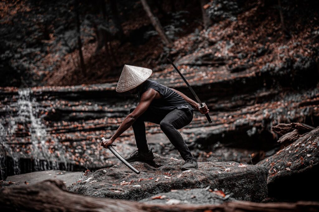 pexels-photo-5971336 A lone samurai crouches with a sword in a serene forest setting, exuding strength and focus.